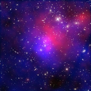 شکل ۱: رنگ آبی نشان‌دهنده‌ی ماده‌ تاریک است. این تصویر برخورد پیچیده و جالب دو خوشه‌ی کهکشانی را نشان می‌دهد. رنگ قرمز داده‌های رصدخانه‌ی چاندرا را نشان می‌دهد. رنگ آبی نیز بر اساس داده‌های هابل و رصدخانه‌های دیگر است که نقشه‌ی جرمی مواد موجود را نشان می‌دهد که به احتمال زیاد، غالبا ماده‌ی تاریک است. تصویر از آرشیو چاندرا برداشته شده است.   Credit: NASA's Chandra X-Ray Observatory